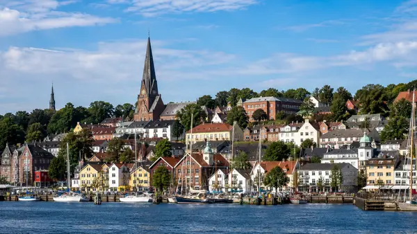 KI-generierte Stadtansicht mit typischen Merkmalen von Flensburg – Hafen und Altstadt am Wasser