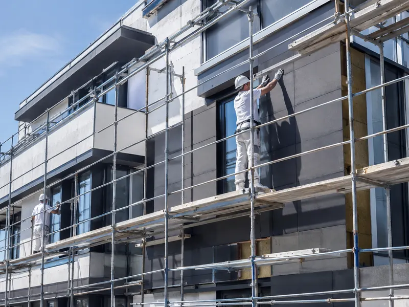 Sanierte und gedämmte Fassade eines Wohngebäudes mit Gerüst